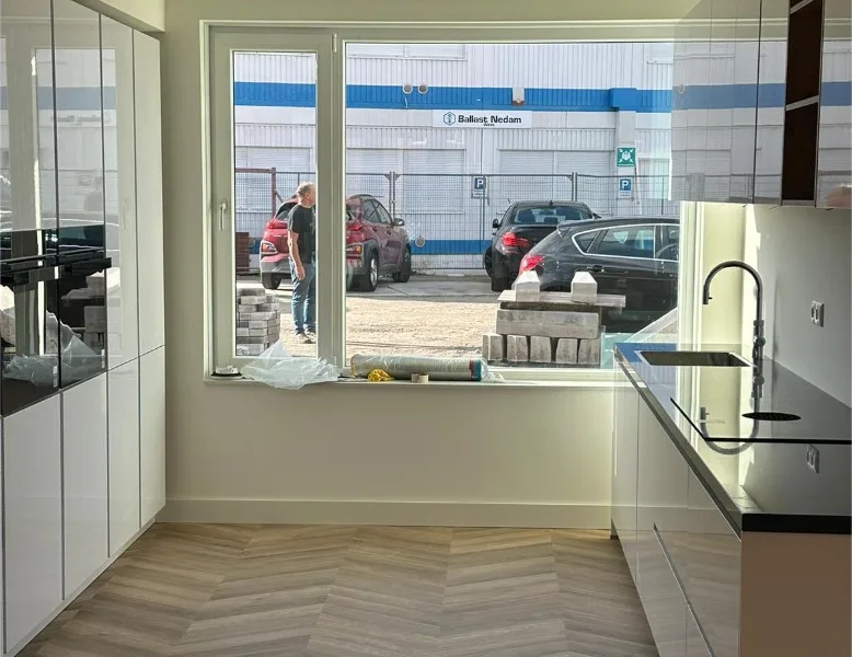 Gerenoveerde keuken met visgraatvloer en zwart werkblad