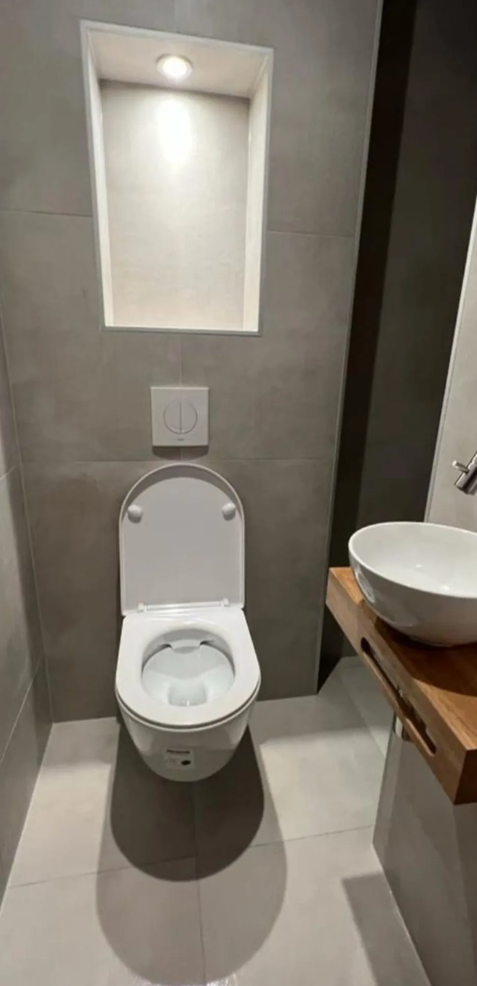 Gerenoveerd toilet met verlichte nis en fonteintje