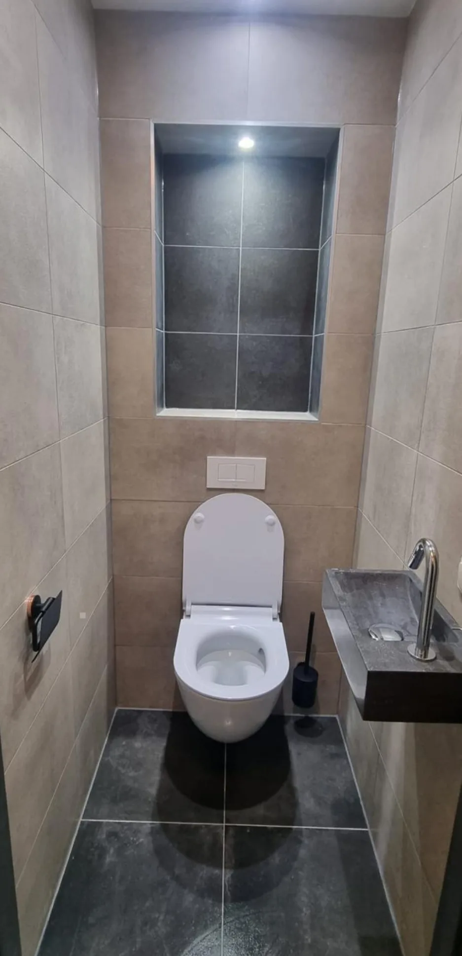 Hangend toilet met verlichte tegelnis en stenen fontein
