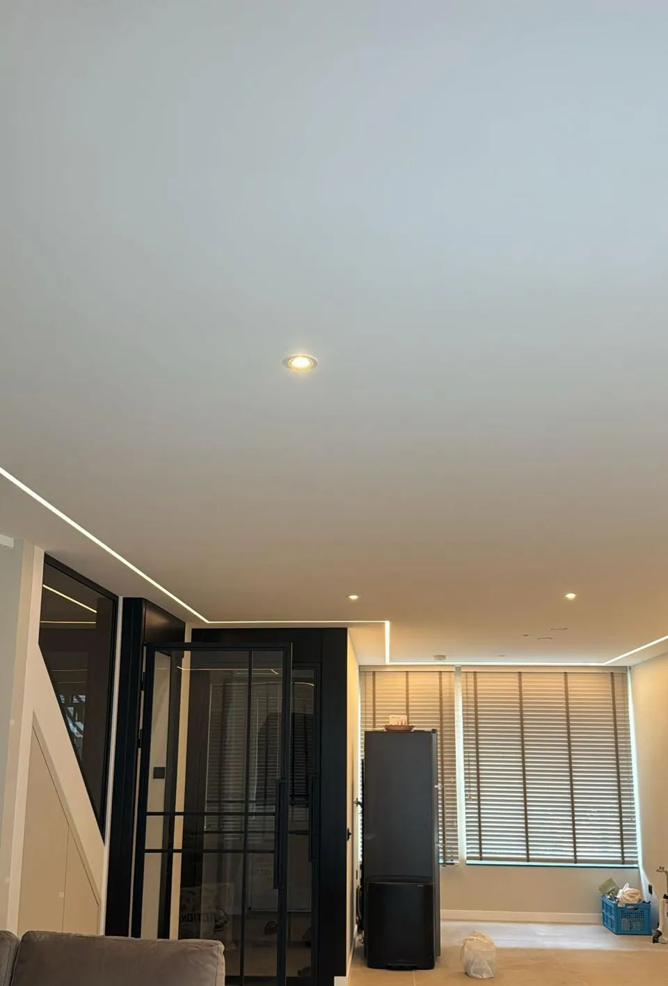 Glad gestuct plafond met inbouwspots en lichtlijnen langs de wanden, met stalen binnendeuren
