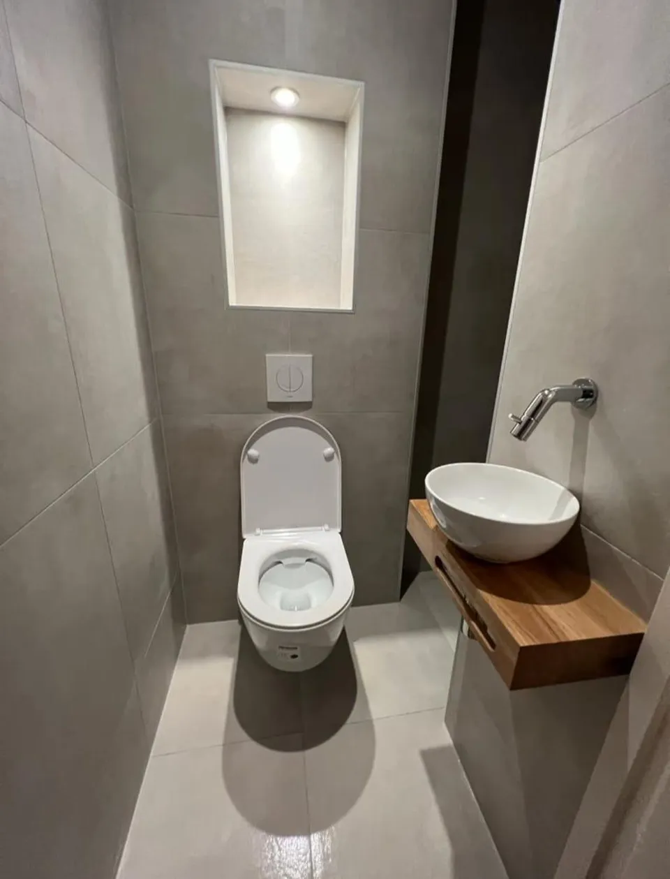 Toilet met verlichte nis, hangtoilet en waskom op een houten plank