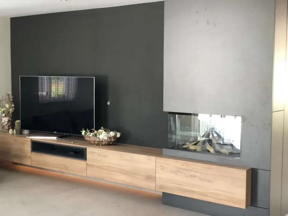 Tv-meubel op maat met ingebouwde haard en betonlook wand