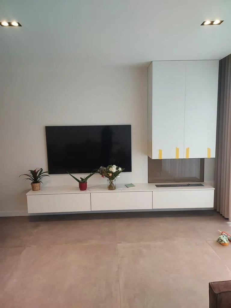 Zwevend wit tv-meubel over de hele wand met een ingebouwde haard onder een witte ombouw